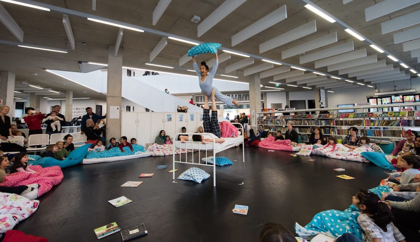 Once Upon a Pillowfight performance. Two dancers perform acrobatics in front of children in a library.