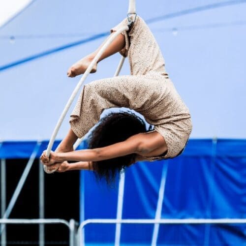Circus Flavours performer on aerial hoop with blue big top in the background