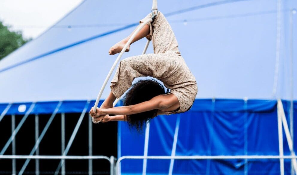 Circus Flavours performer on aerial hoop with blue big top in the background