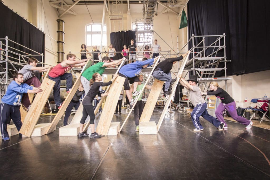 A group of people lean towards each other on planks of wood