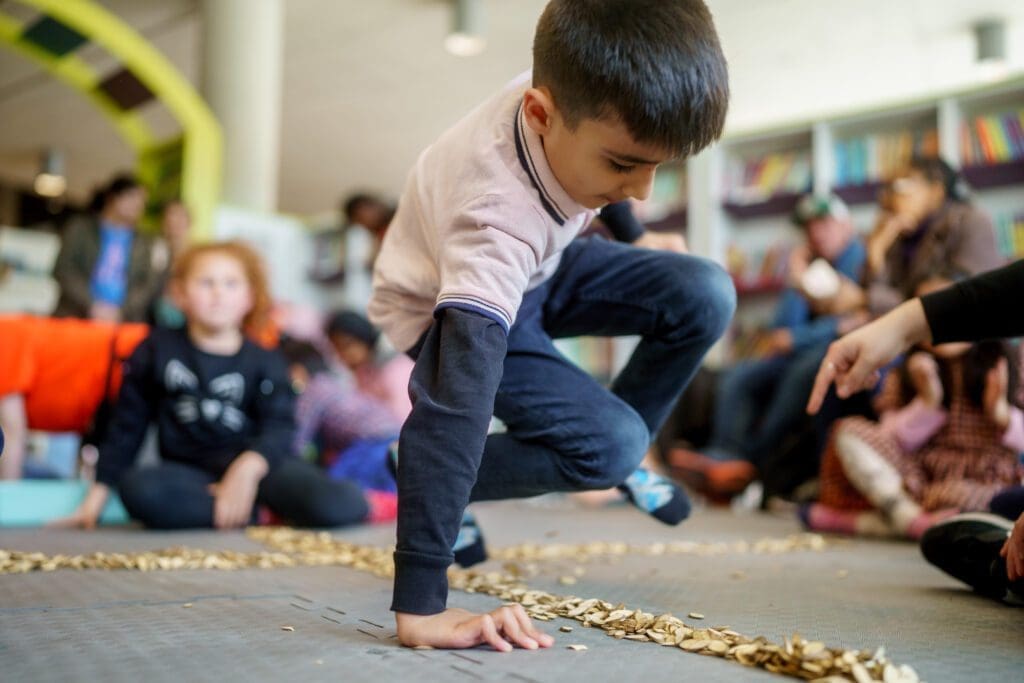A young child jumps over some seeds spread on the ground
