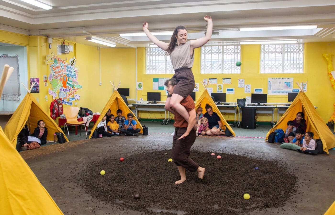 Seasons performance in libraries. Two acrobatics perform a move in front of an audience