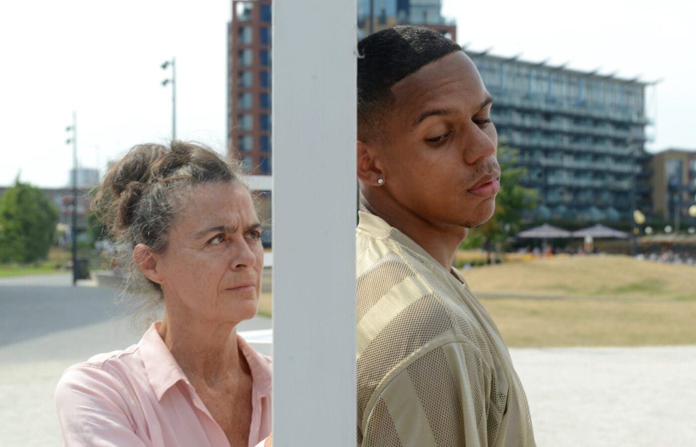 A caucasian female in her sixties and a black male in his twenties stand outside