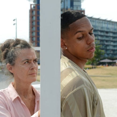 A caucasian female in her sixties and a black male in his twenties stand outside