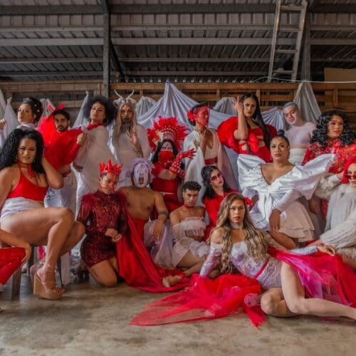A big group of performers dressed in lavish in red and white costumes pose together