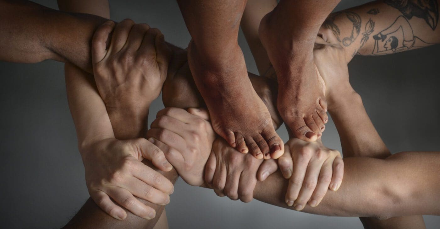 Pairs of hands hold together in a basket weave with a pair of feet standing on top