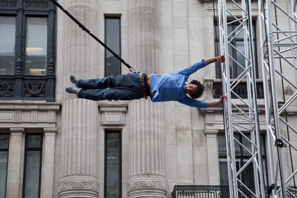 A man holds himself in the air, holding onto some scaffolding