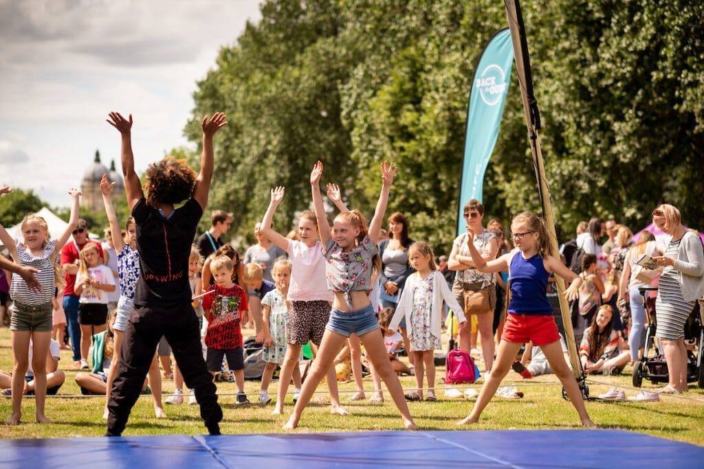 a circus workshop leader teaches children some circus moves