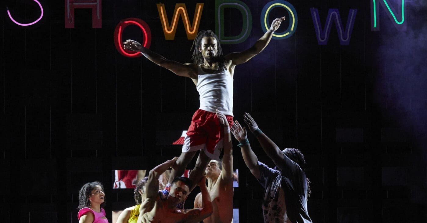 A circus artist is lifted into the air by 6 other acrobats