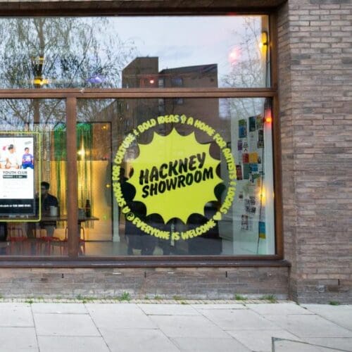 A photo of a shop window with big round yellow 'hackney showroom' logo sticker on the window