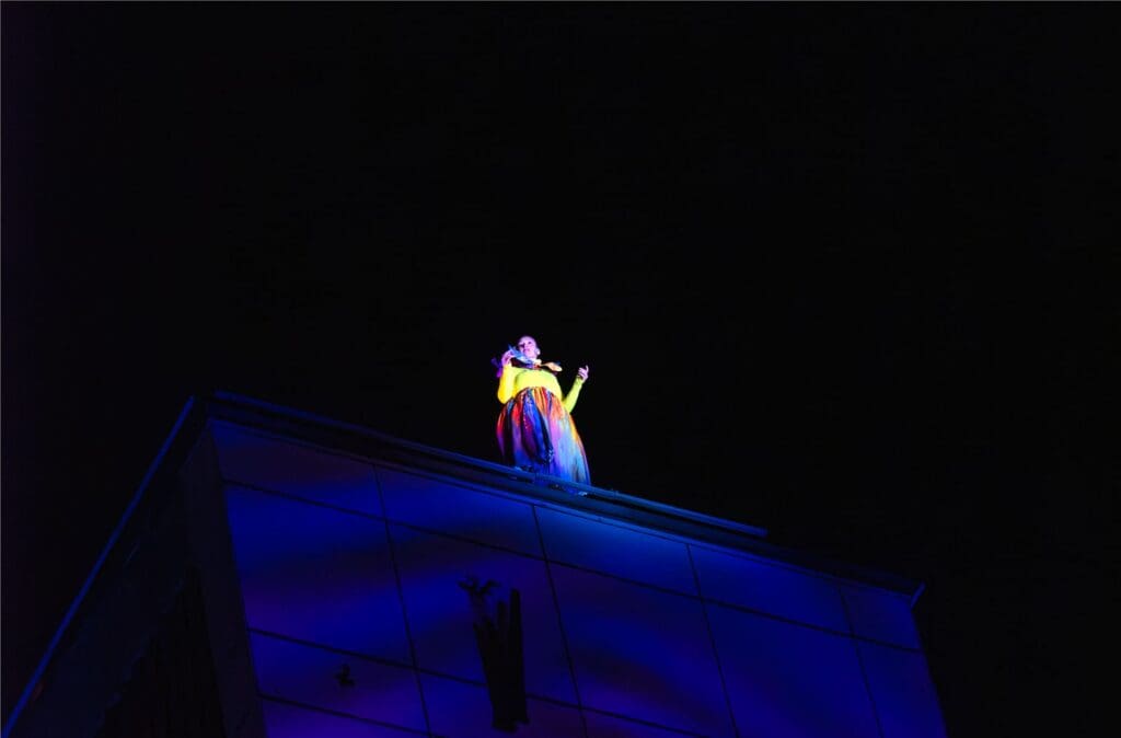An opera singer stands on top of shipley clocktower building
