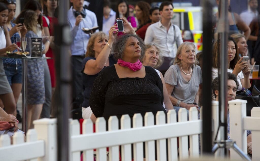 A large outdoor audience looks up towards the sky
